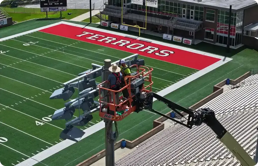 Two electricians fix stadium lighting at Terrors football field